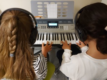 Två elever spelar piano tillsammans